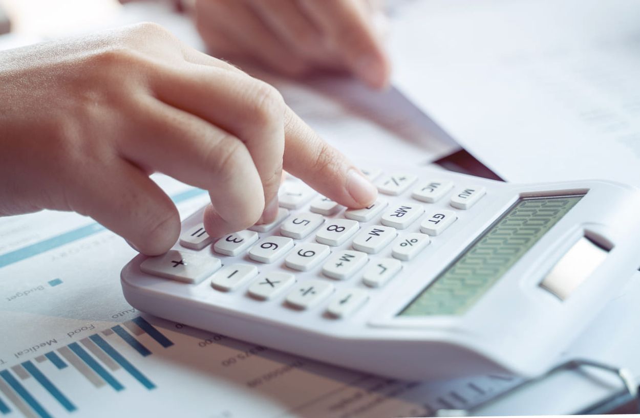 Person rechnet etwas mit einem Taschenrechner aus